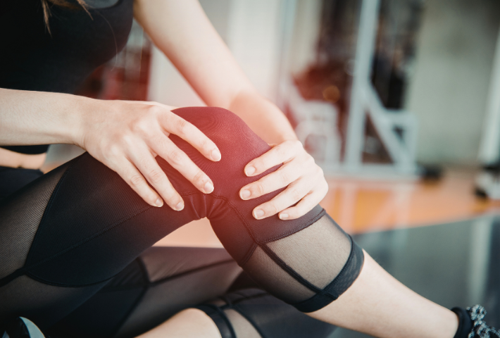 Donna che si tocca il ginocchio dolente a causa di un edema post-operatorio.